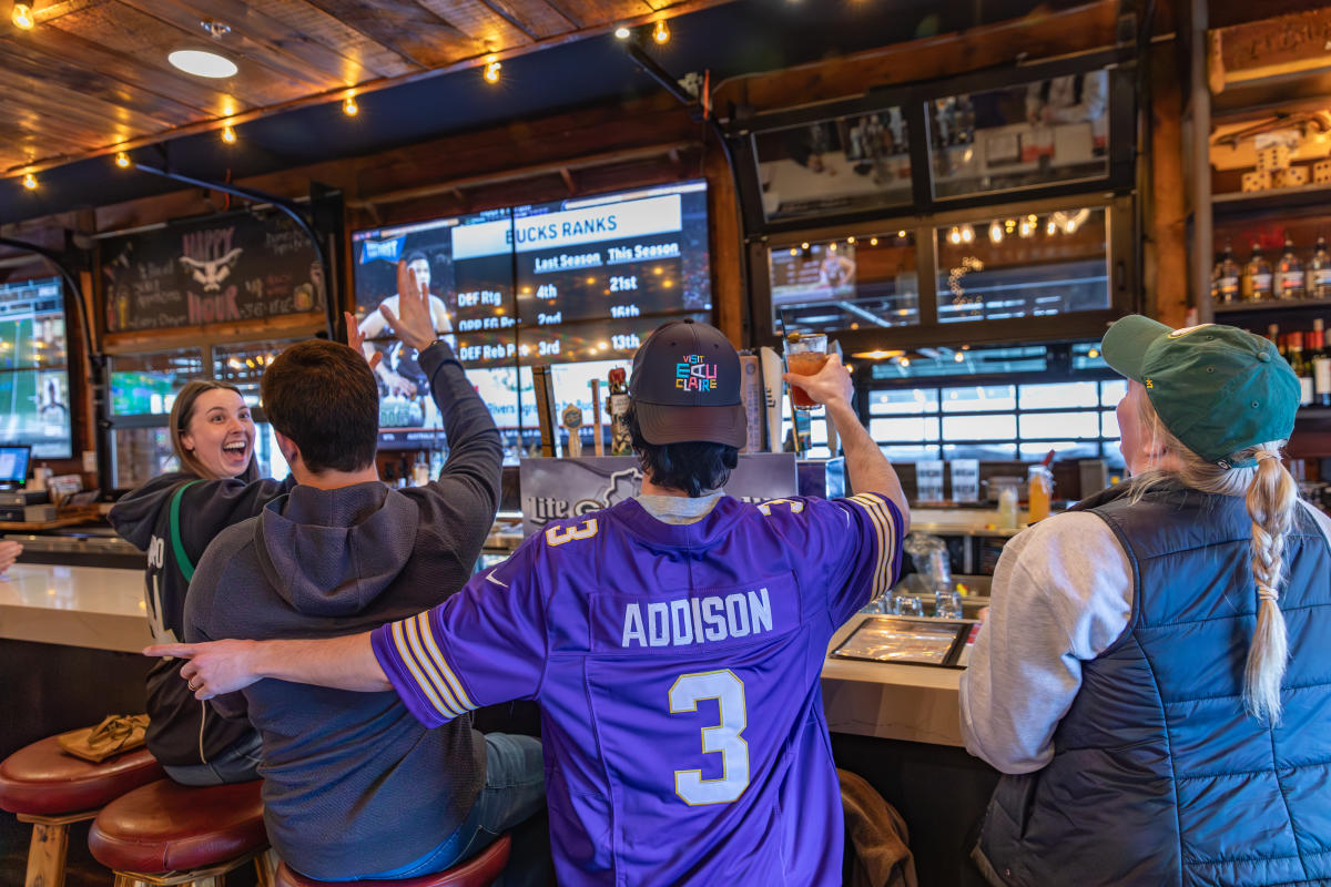 A group of friends sitting at the bar at Cowboy Jack's watching sports and having drinks