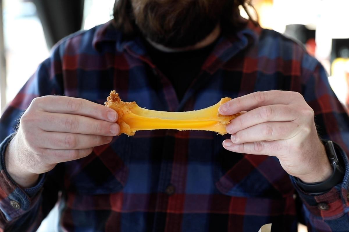 A man pulling apart a large cheese curd at The District in downtown Eau Claire