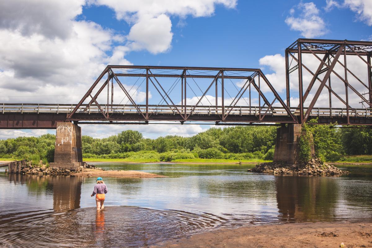 A girl playing in the river in front of a bridge at the Dunnville State Wildlife Area