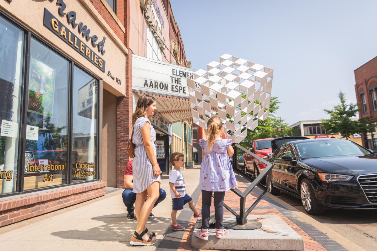 A family of 4 walking down Barstow Street looking at sculptures