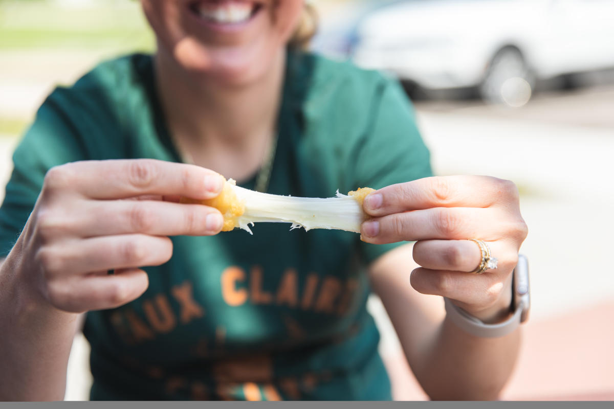 A woman pulling apart a fried cheese curd at Ellsworth Cheese Factory in Menomonie, WI