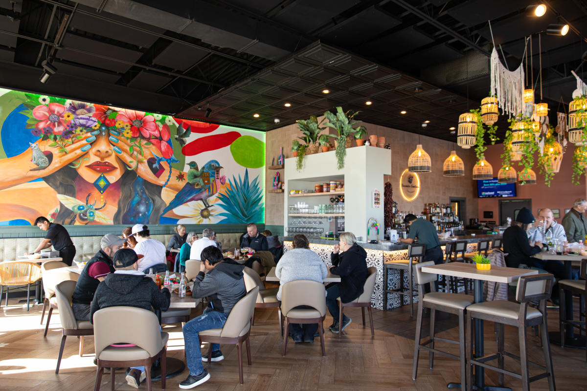 Inside the restaurant of Encanto Cantina with a colorful mural and plants hanging from the ceiling