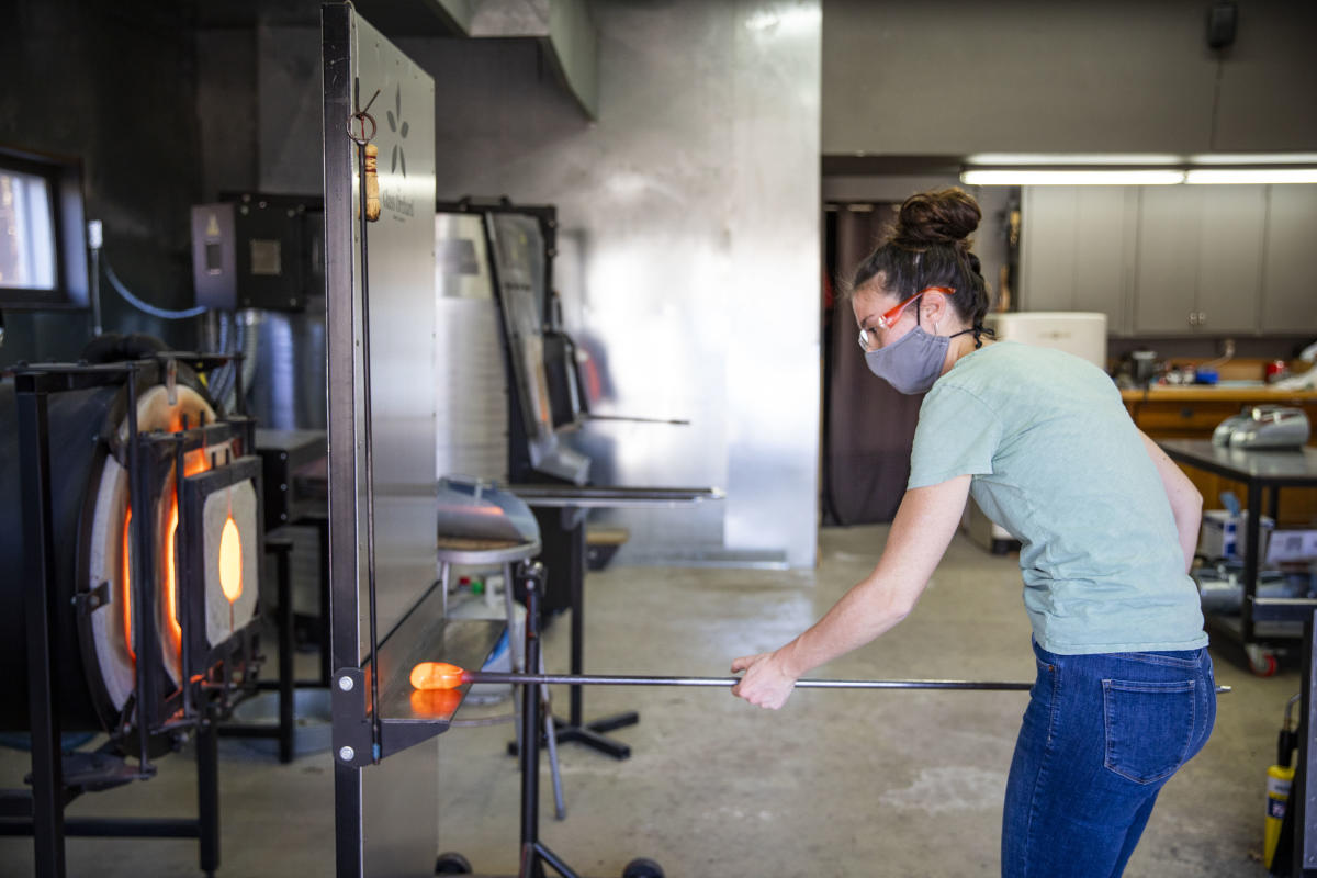 Woman working with hot glass to mold In the glass studio at The Glass Orchard