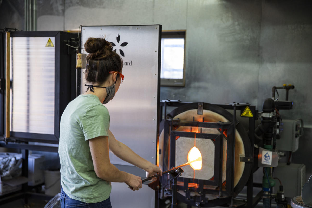 Woman wearing a mask while working In the glass studio at The Glass Orchard