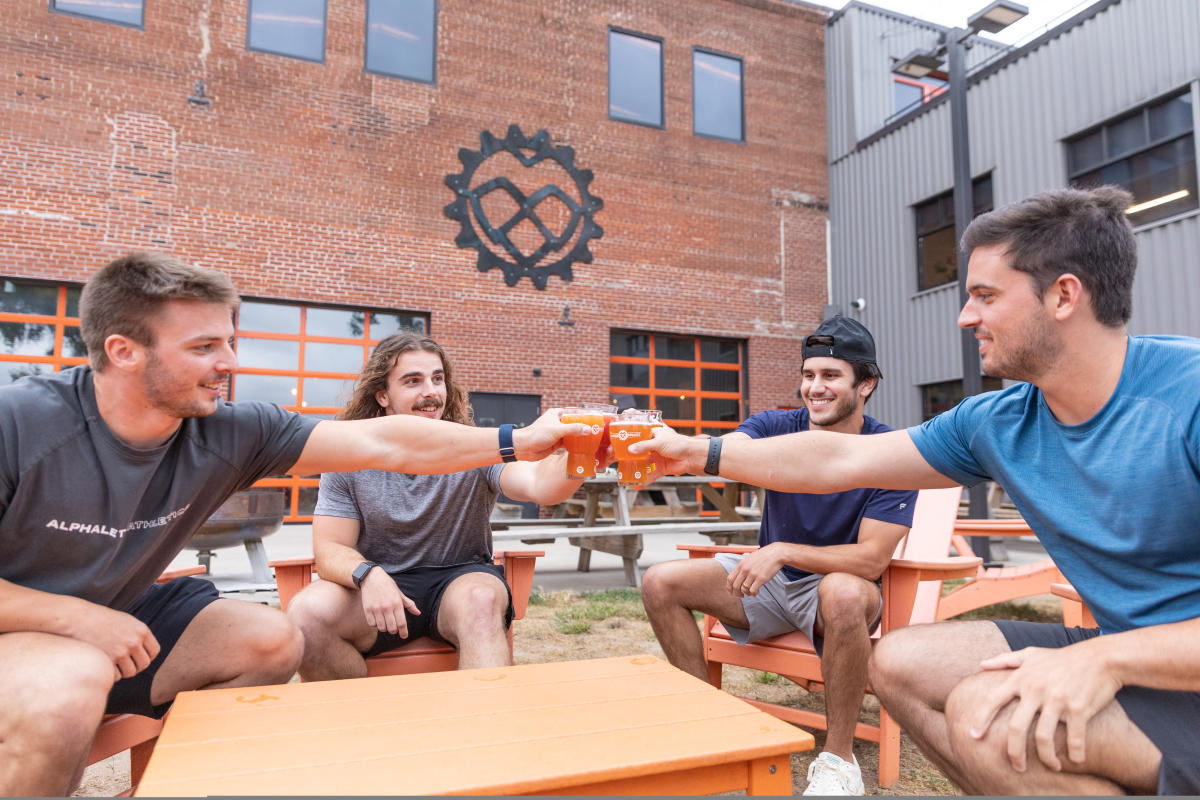 A group of guys cheers their beers on the outdoor patio at The Brewing Projekt in downtown Eau Claire