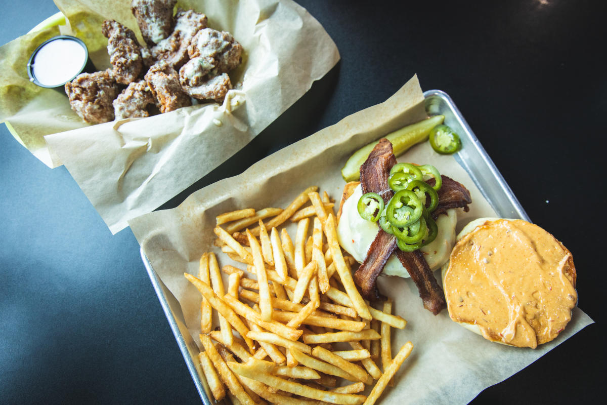 a photo of chicken wings and a burger with jalapeños and bacon with french fries at Hangar 54