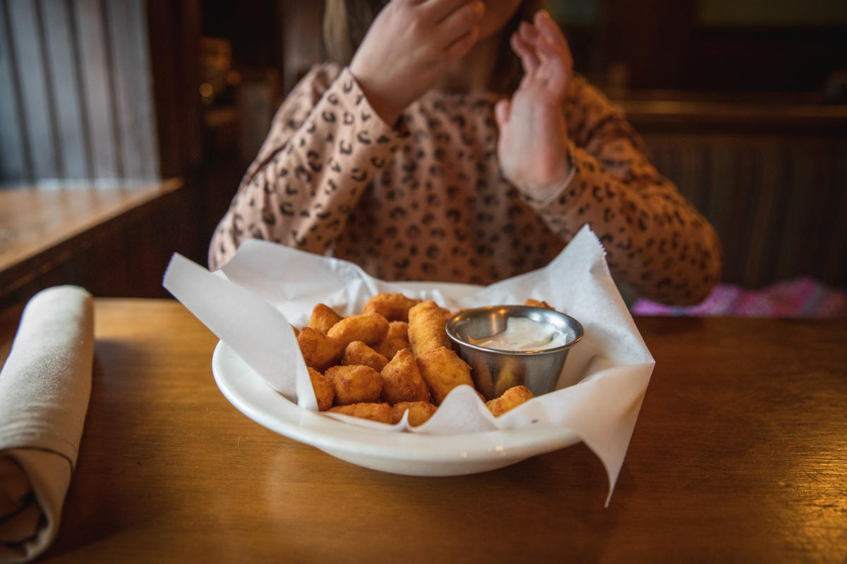 A young girl eating cheese curds at Houligans Steak & Seafood Pub