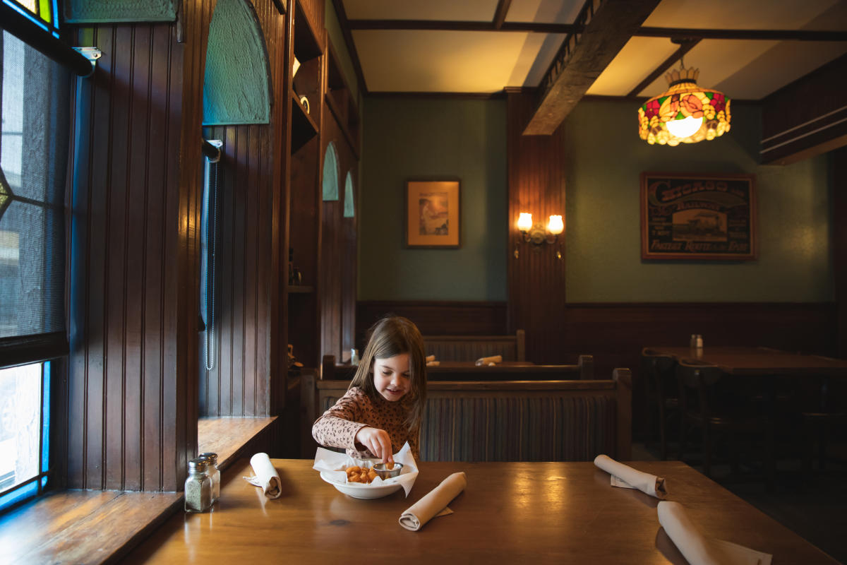 A young girl eating cheese curds at Houligans Steak & Seafood Pub