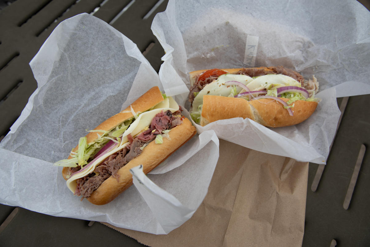 Two sandwiches on a table outside of Jay Ray's Deli