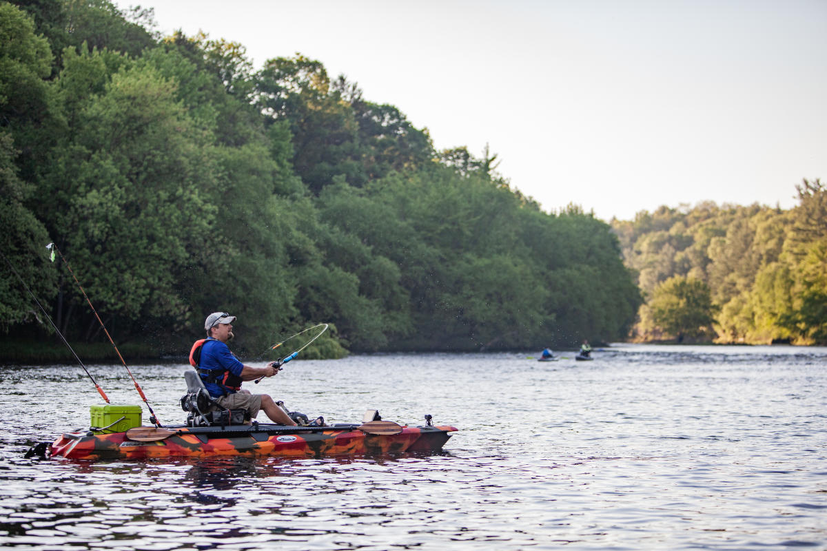 A man fishing for Bass in a kayak in the Eau Claire River