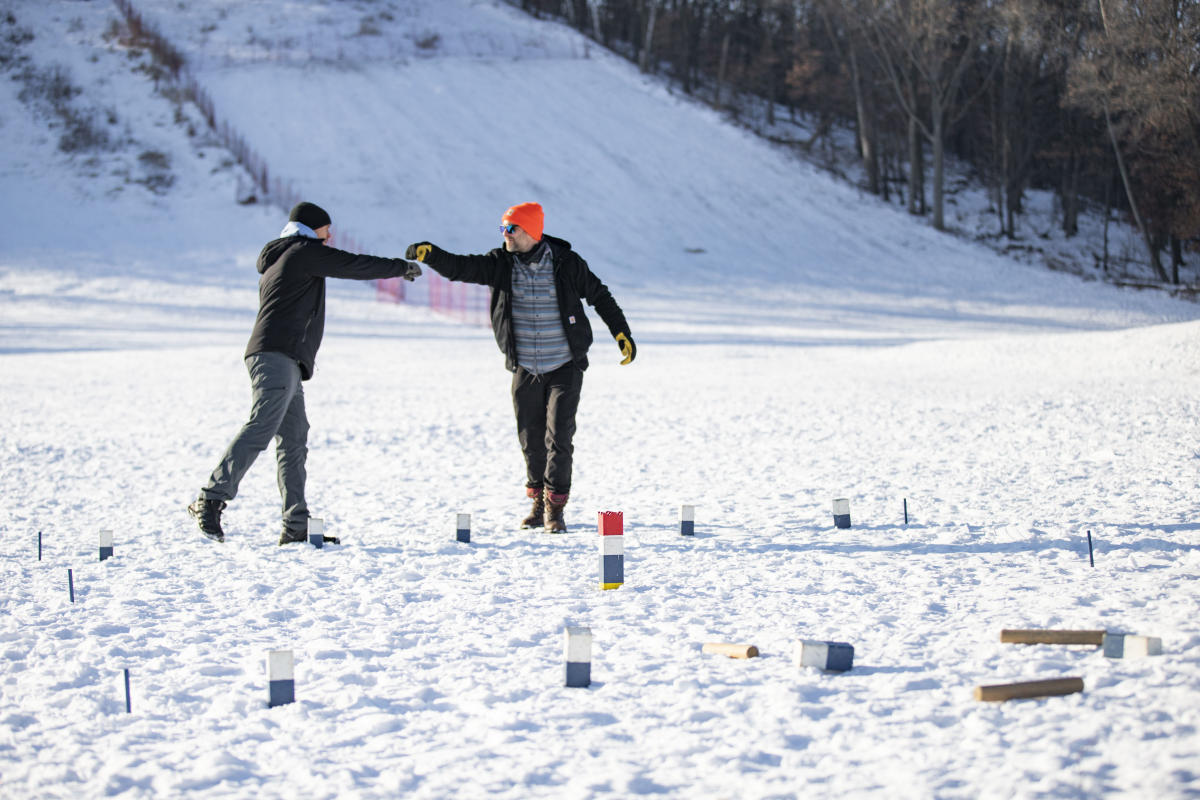 Two men playing Kubb in the snow at Pinehurst Park