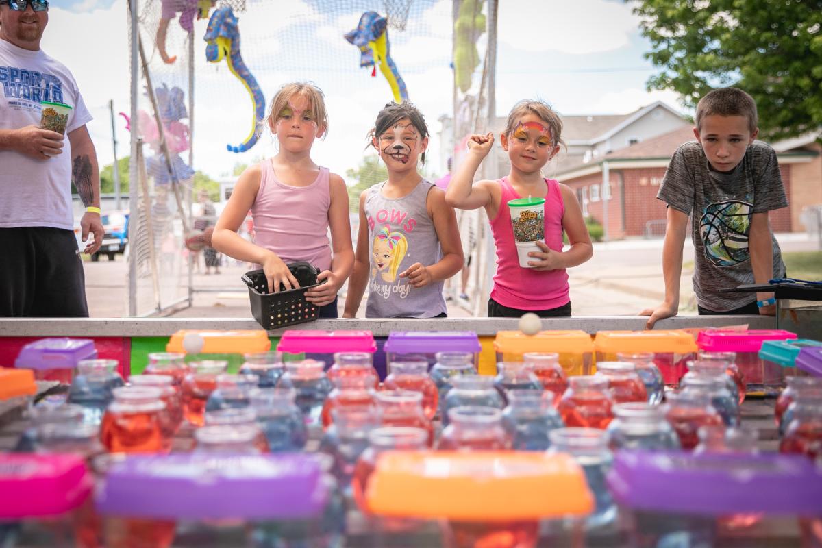 A group of 3 little girls with their faces painted playing carnival games at Lake Martha Days in Osseo 2021