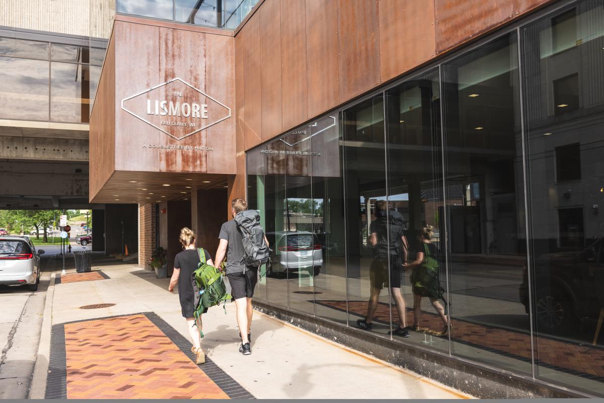 A couple carrying their luggage into the lobby of The Lismore Hotel