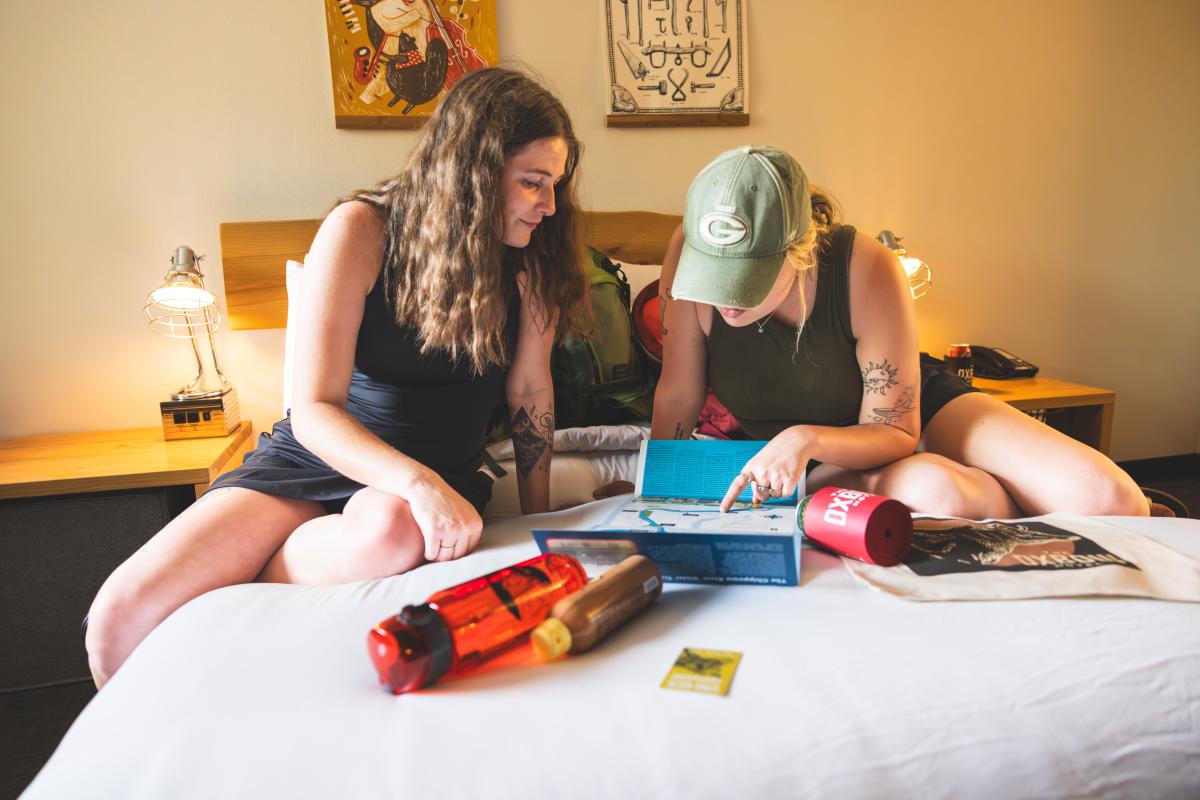 Two girls reading an informational poster inside a room at The Oxbow Hotel