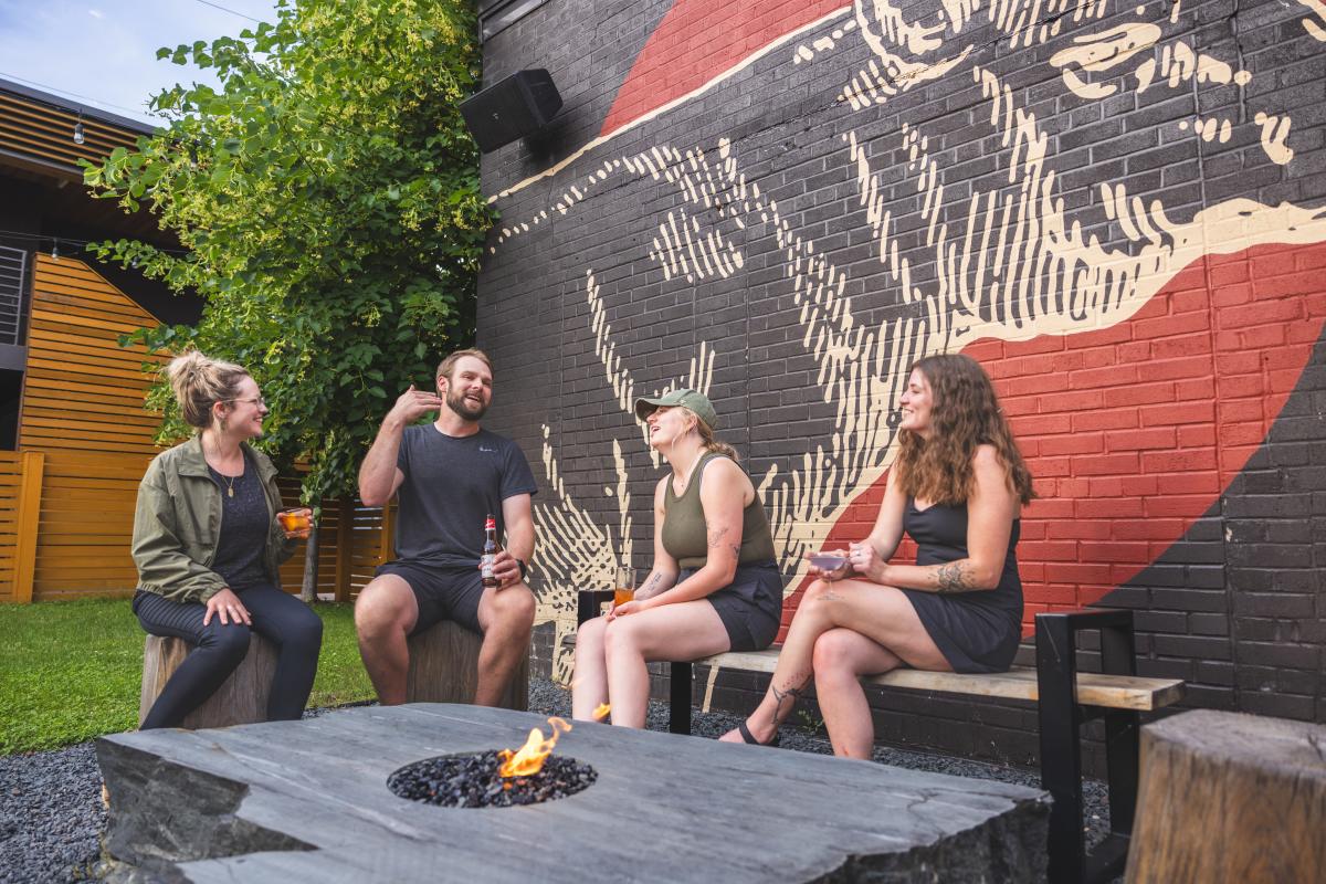 A group of 4 people sitting around a fire at The Lakely