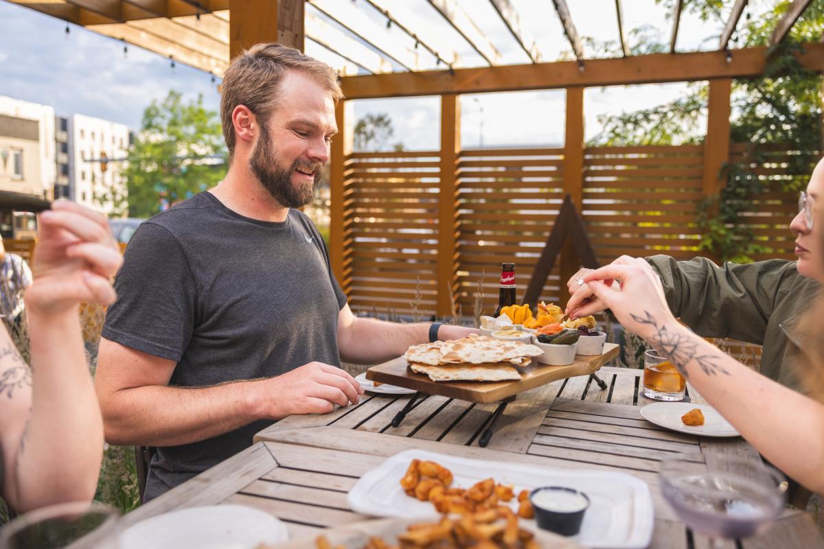 A group of friends sharing appetizers on the patio at The Lakely