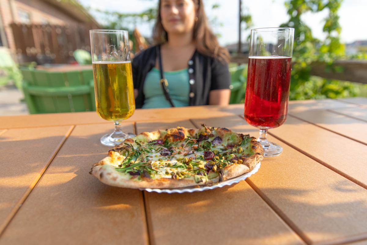 A wood-fried pizza with two beers on the patio at Modicum