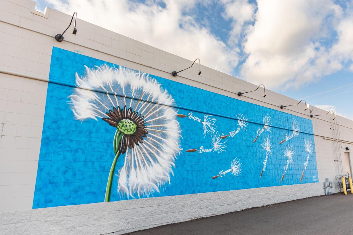 A mural of a dandelion's seeds blowing away