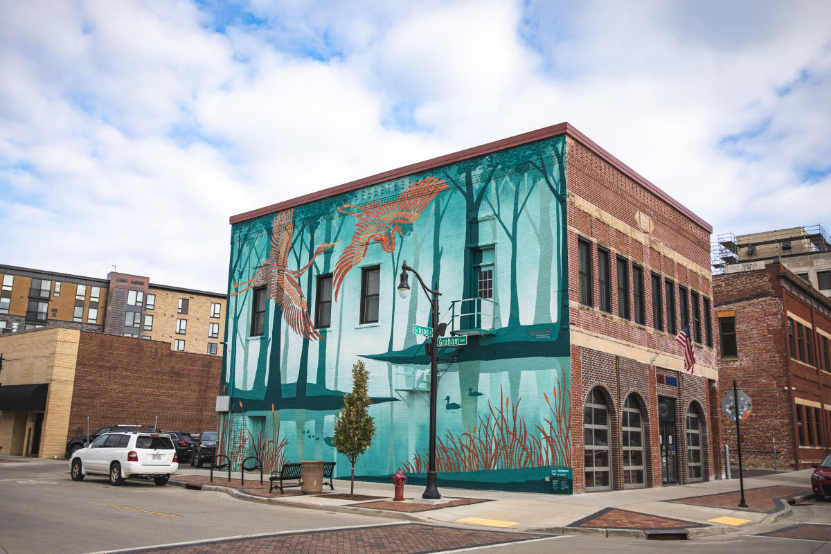 The mural located on the side of the Firehouse in downtown Eau Claire featuring teal/blue colors and copper colored birds