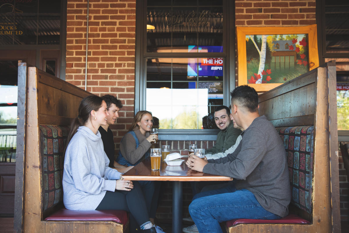 A group of friends dining on the porch and drinking beer at the Northwoods Brewpub in Osseo, WI