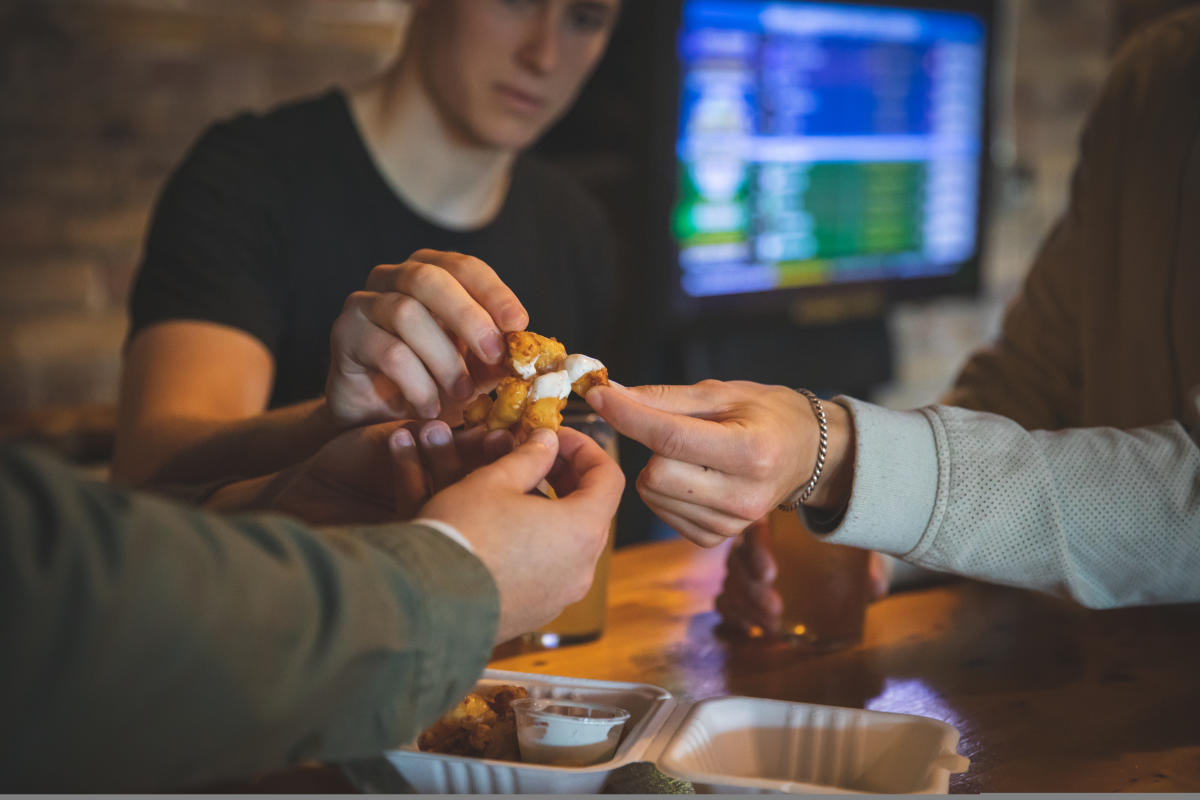 A group of guys eating cheese curds dipped in ranch from Northwoods Brewpub in Osseo, WI