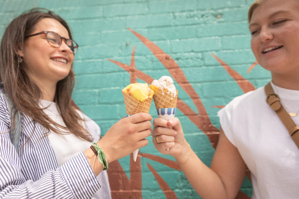 Two girls holding ice cream cones in front of a mural in Eau Claire