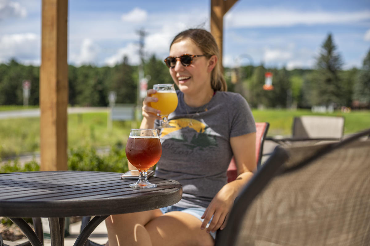 A woman enjoying a beer on the outdoor patio at Ombibulous Brewing Company in Altoona, WI