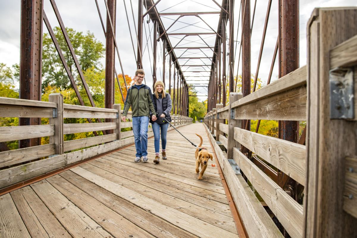 Couple walking their dog on a leash across Phoenix Park Bridge