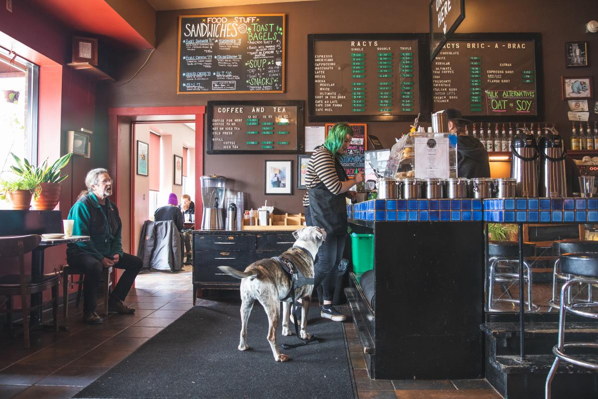 a girl ordering a coffee while a dog is standing next to her at Racy's Coffee House