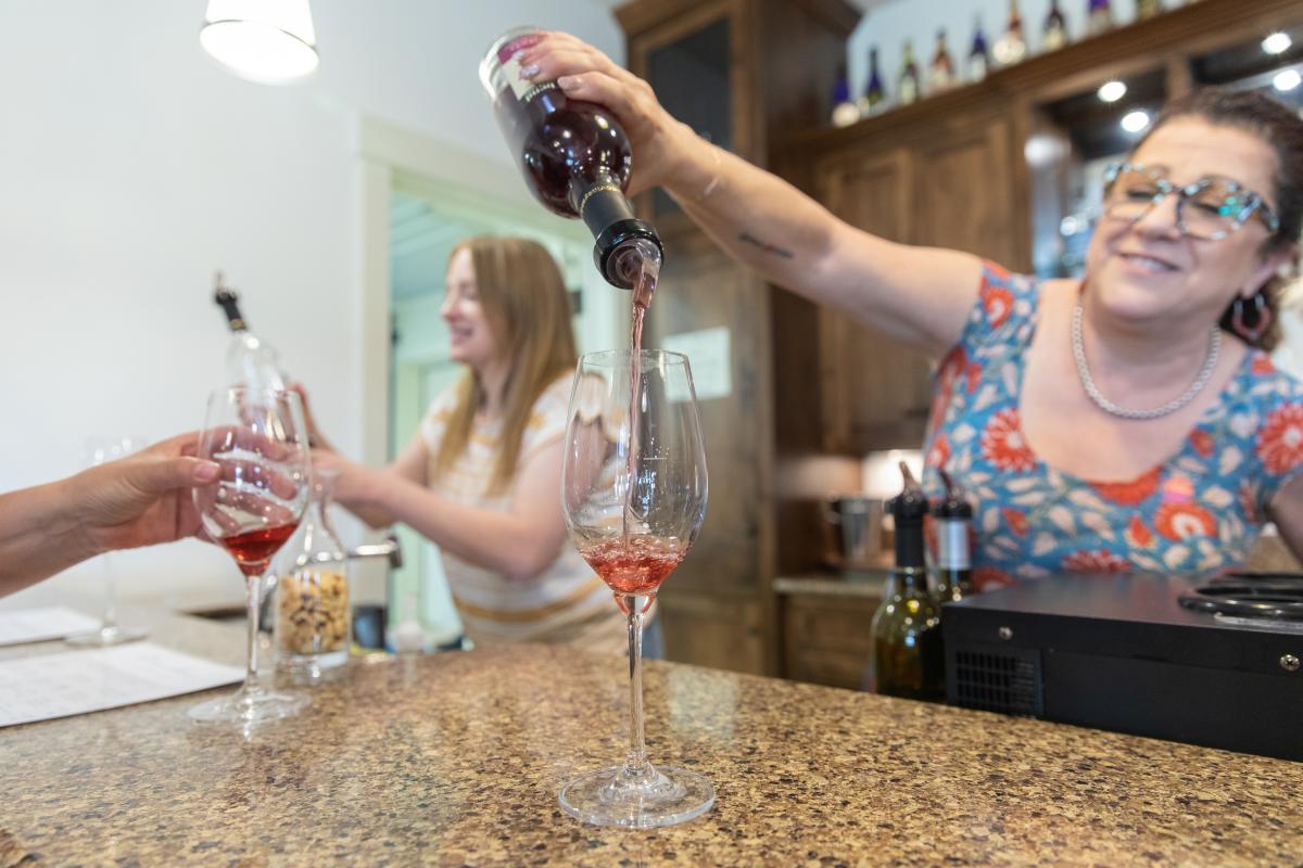 a lady pouring a sample of wine into a wine glass at River Bend Winery