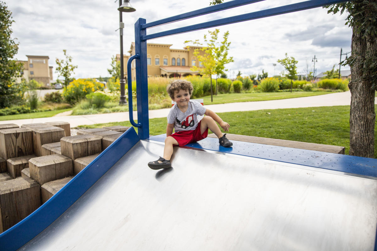 Young boy playing on a slide at the River Prairie playground