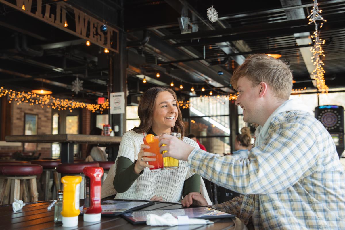 A male/female couple cheers their beers on the outdoor patio at Cowboy Jacks in Altoona in the winter