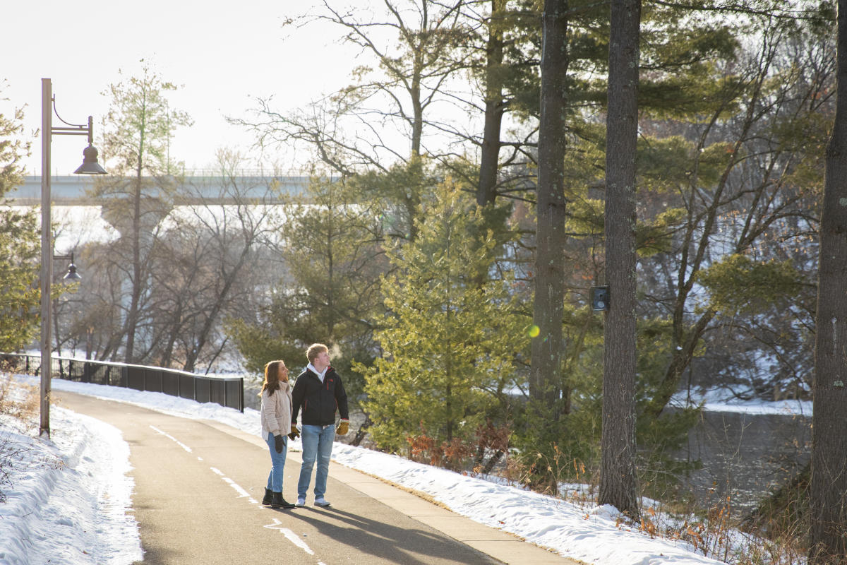 A couple walking along the trail by the river in River Prairie in the winter
