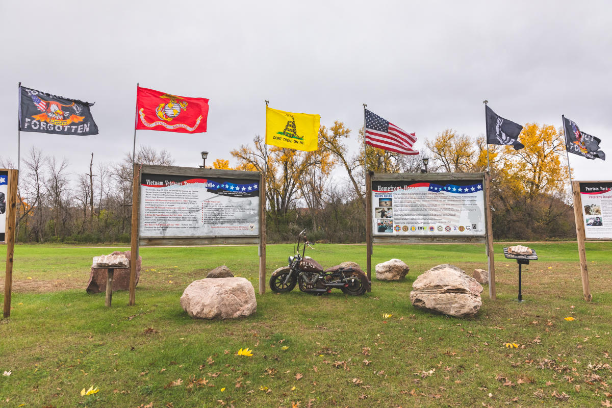 a photo of flags, signs, and an old motorcyle at a Veteran's Tribute in Eau Claire