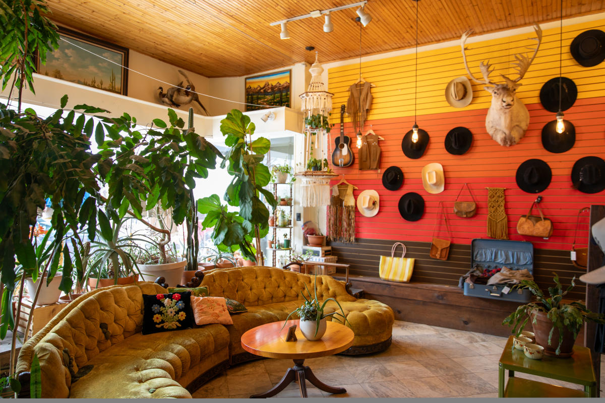A warm, colorful wall lined with hats and a couch next to it