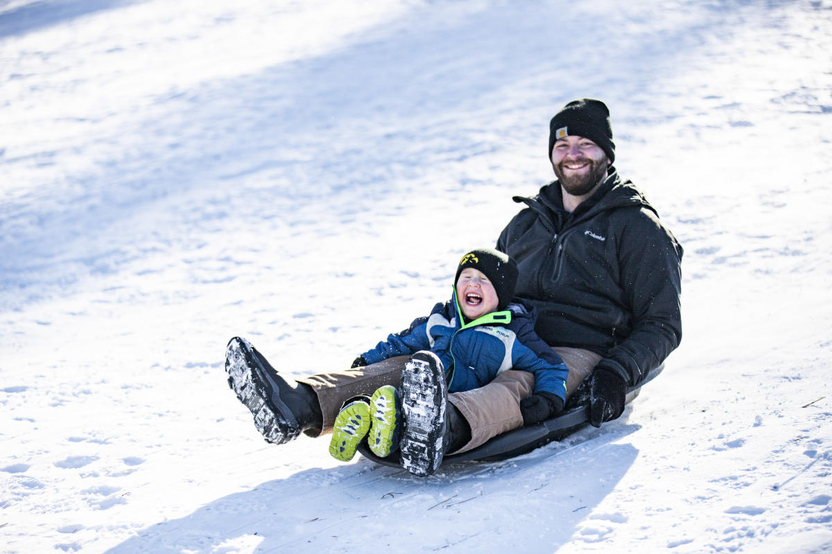 A man and a little boy sledding at Pinehurst Park