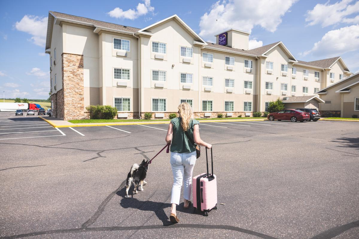 A girl walking into Sleep Inn & Suites with a dog and suitcase