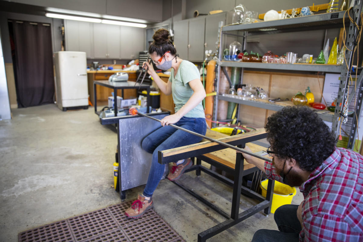 A man and woman duo blowing glass together at The Glass Orchard