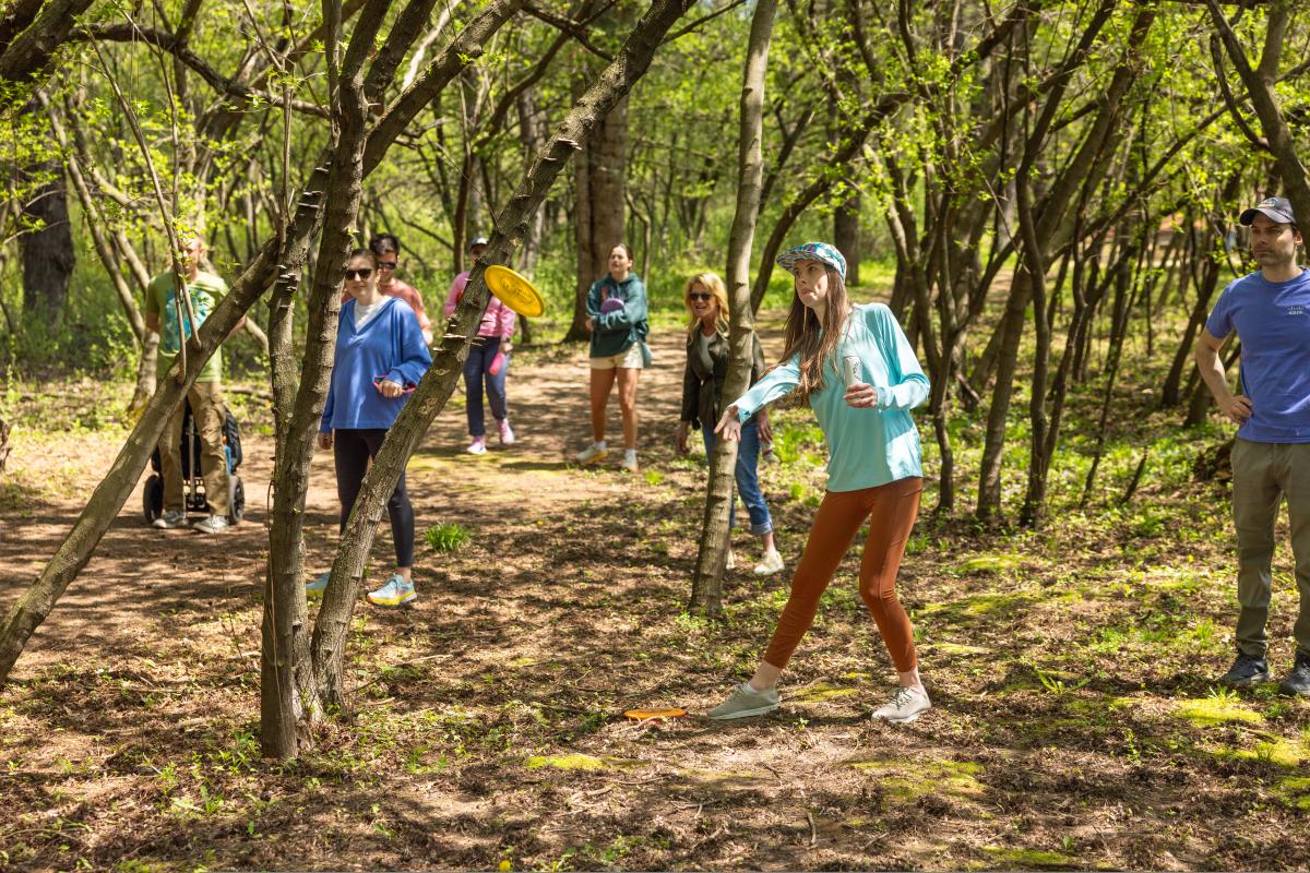 A group of people playing disc golf in the woods