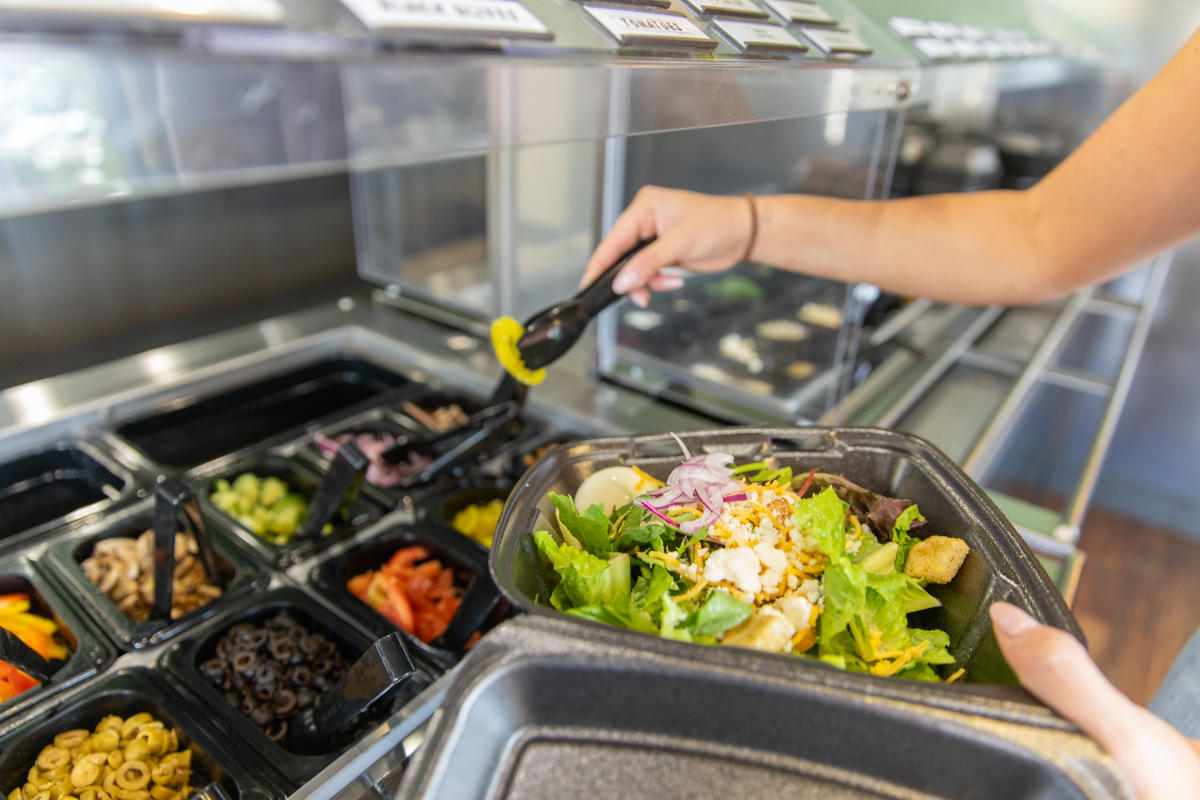 A girl dishing up a salad at Cast Iron Pizza