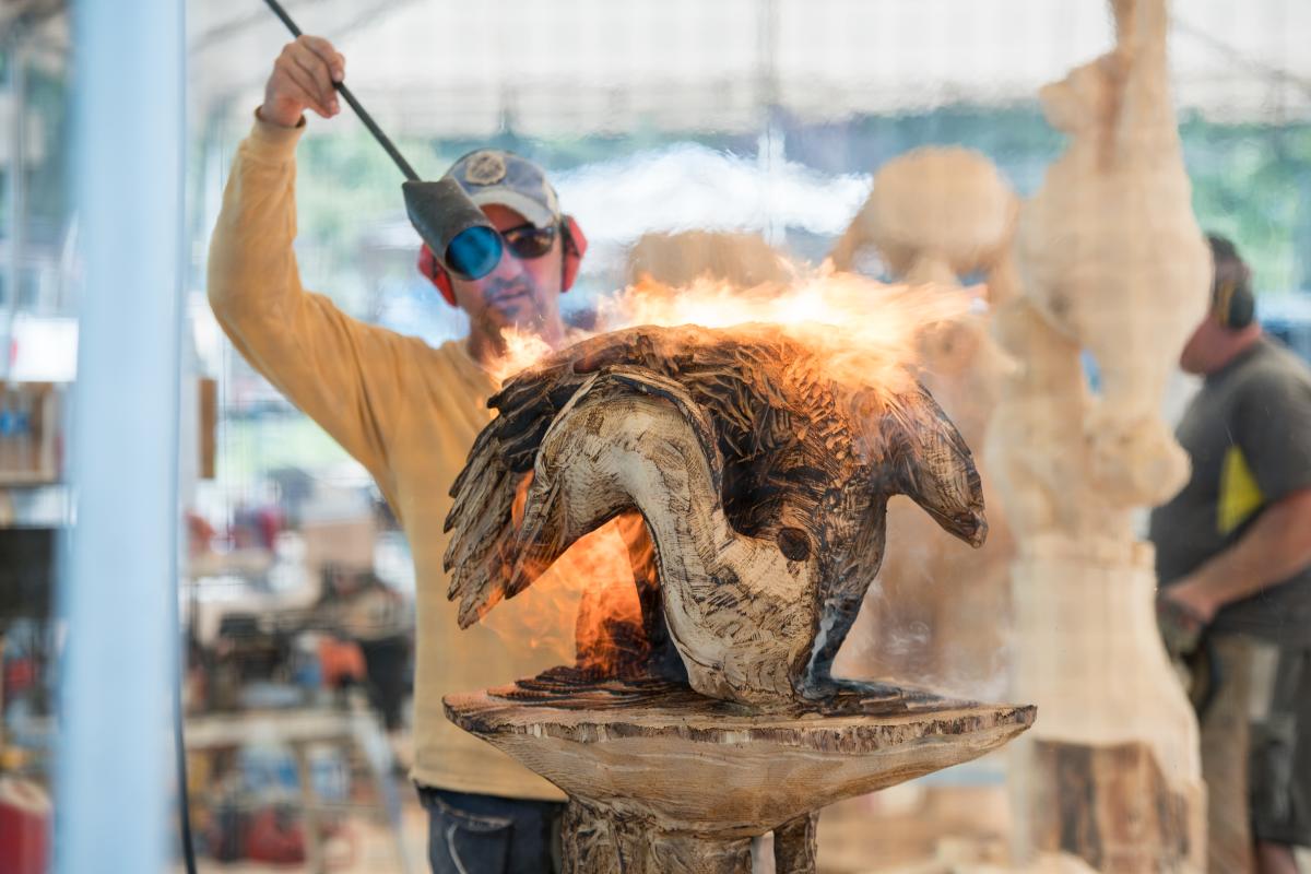 A man torching a wooden sculpture