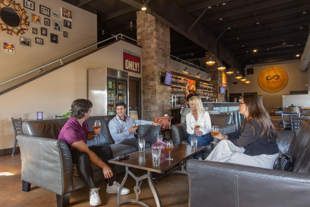 A group of people lounging on couches and having drinks at Infinity Beverages