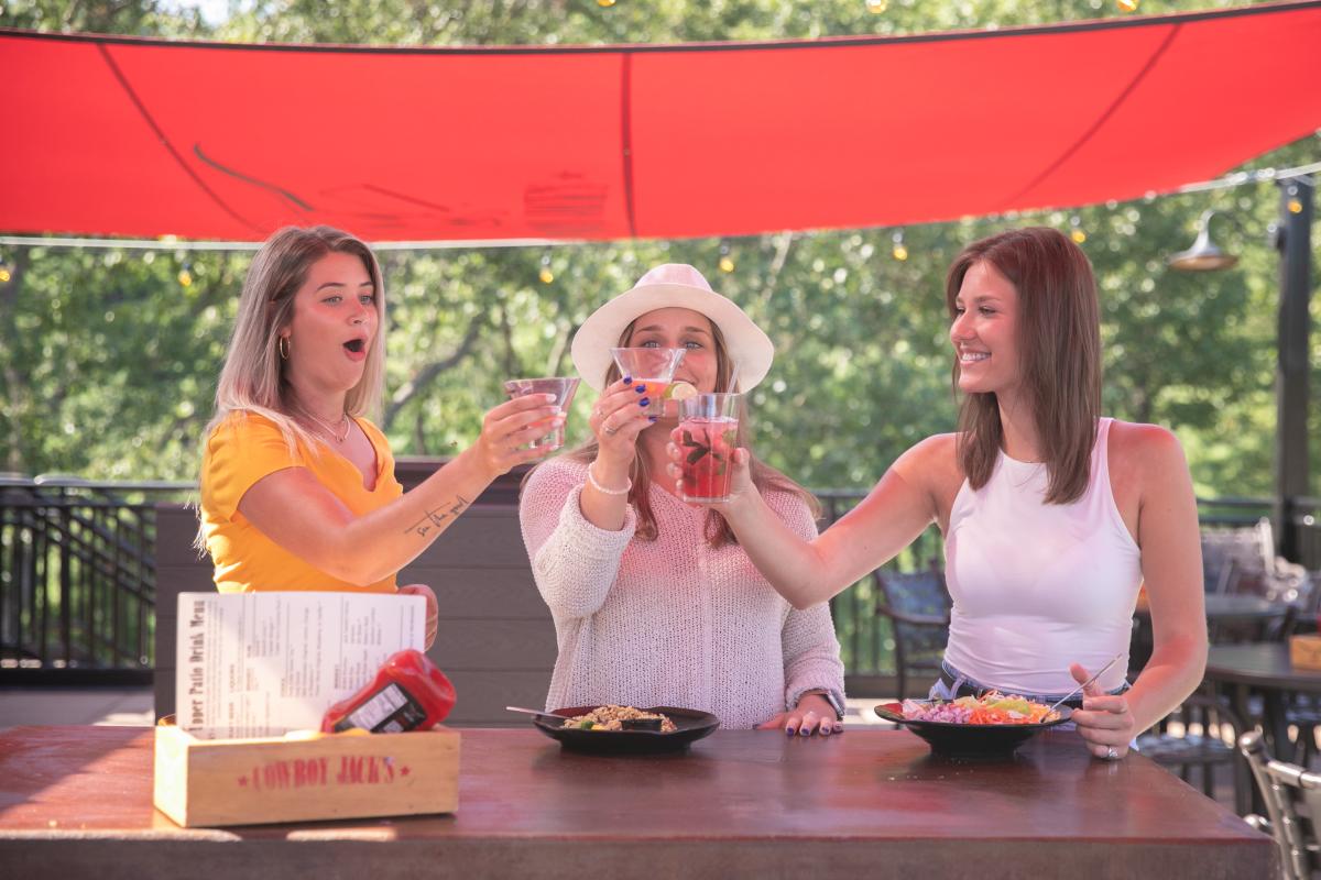 3 girls doing a cheers with their drinks on the patio at Cowboy Jack's