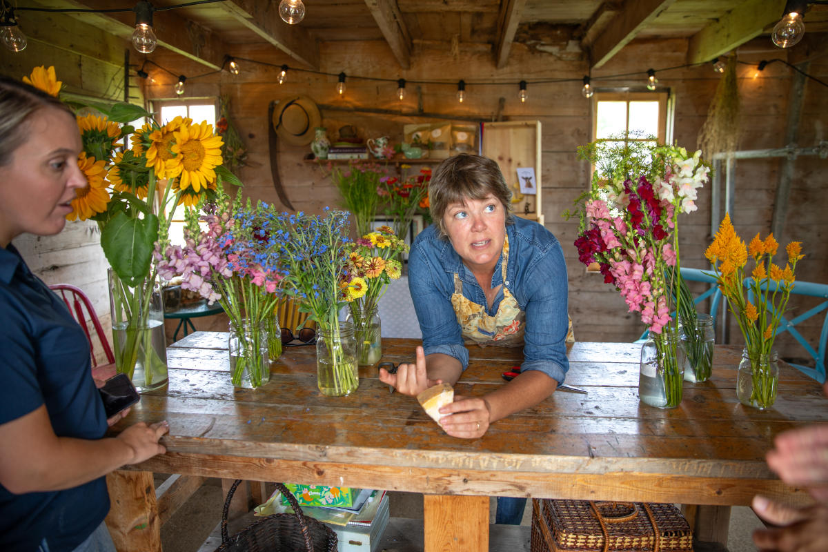 A woman talking about cheese while surrounded by flowers in a farm stand