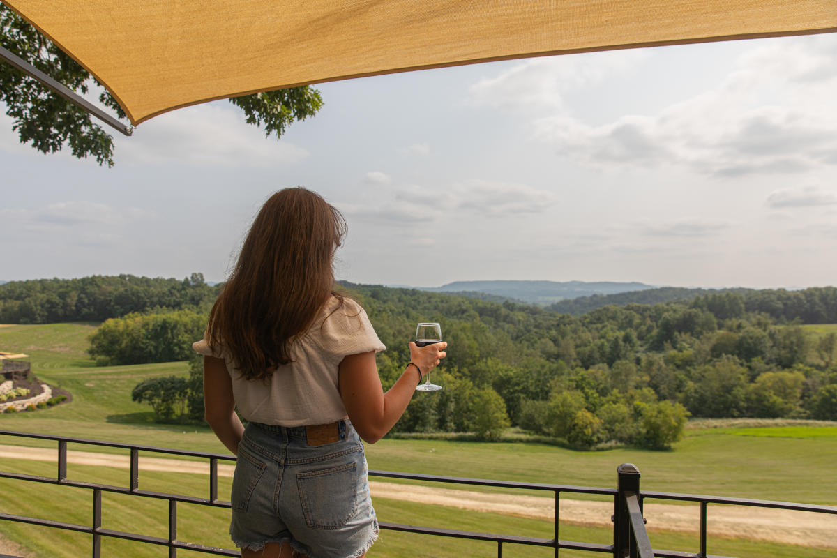 A girl drinking wine and look at the view of hills at Tenba Ridge Winery