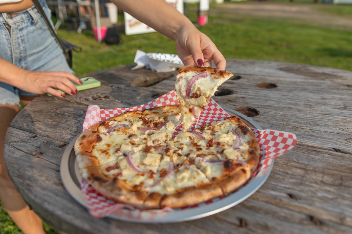 A girl grabbing a slice of pizza at Woodshed Pizza Farm