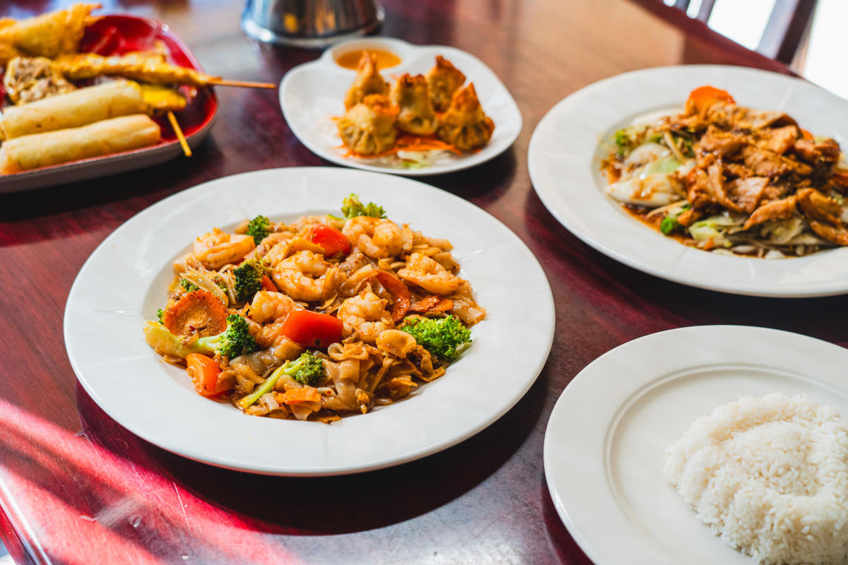 Variety of Thai dishes including pad Thai, dumplings, and satay