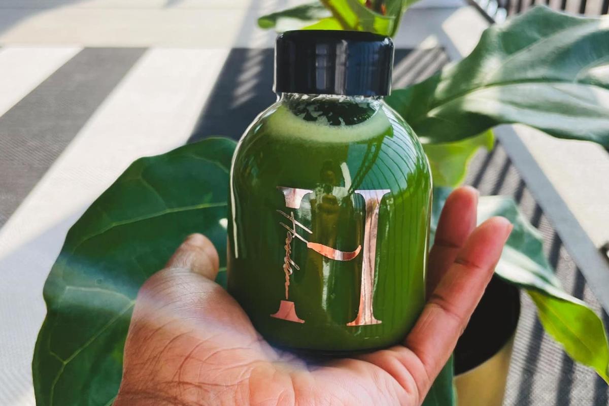 a bottle of green juice from harlow the juice bar in a perons hand