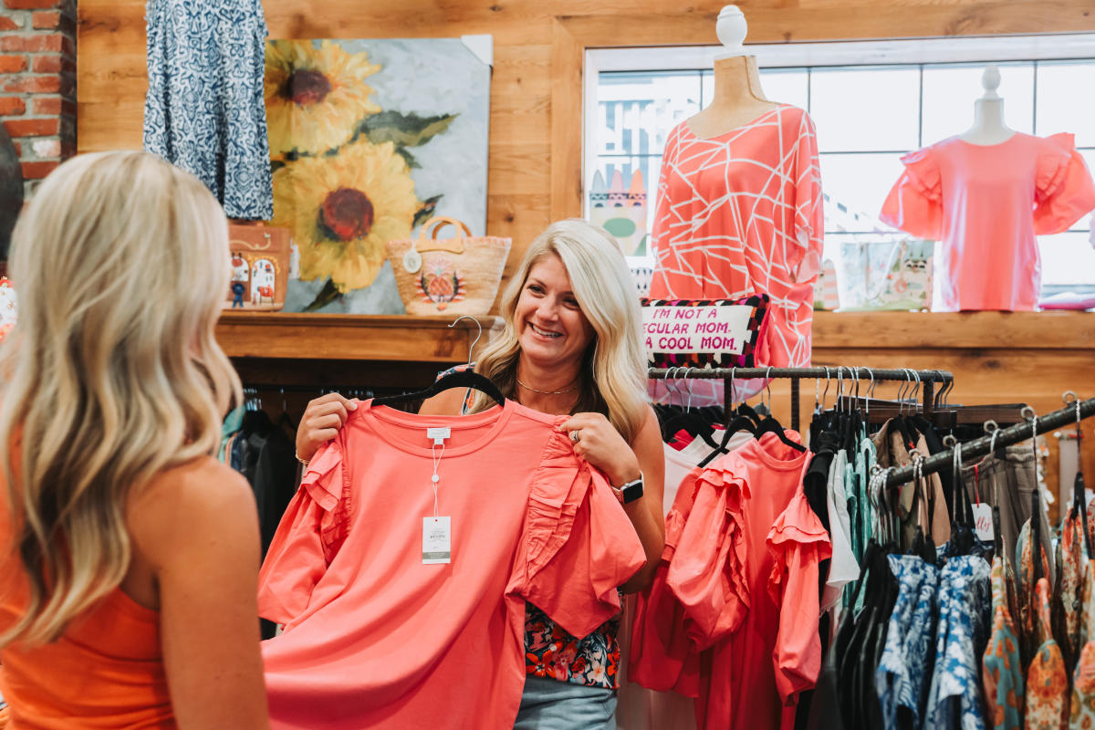 Two woman holding onto a coral shirt while shopping in The Bug's Ear in Downtown Elizabethtown