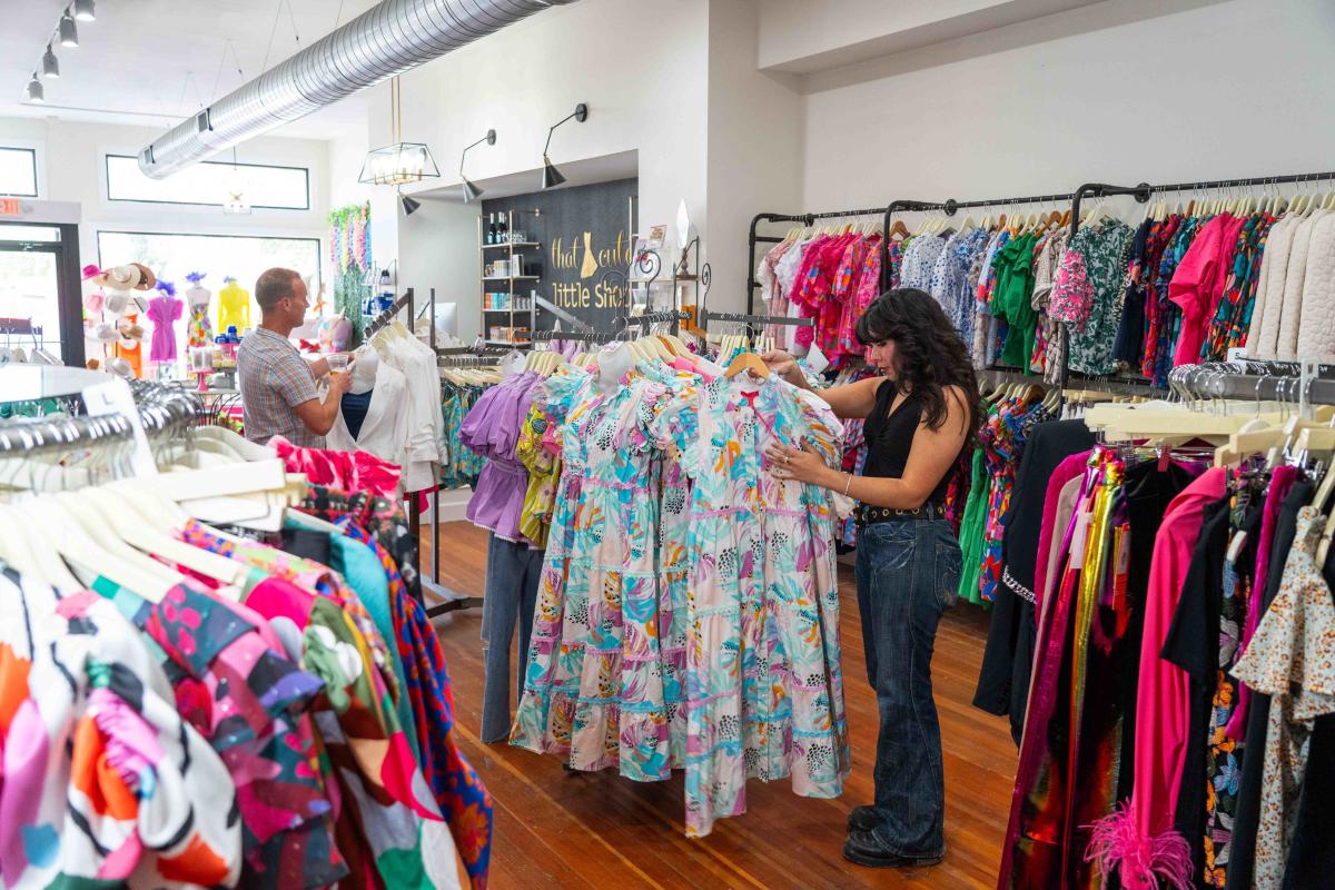 A lady is looking at a multi-colored long dress in the middle of That Cute Little Shop in Downtown Elizabethtown